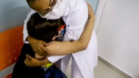 Criança abraça enfermeira após se vacinar - Reprodução / Aloiso Maurício / Foto Arena / Estadão