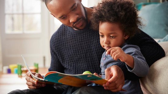Pai lê para filho em casa - Getty Images