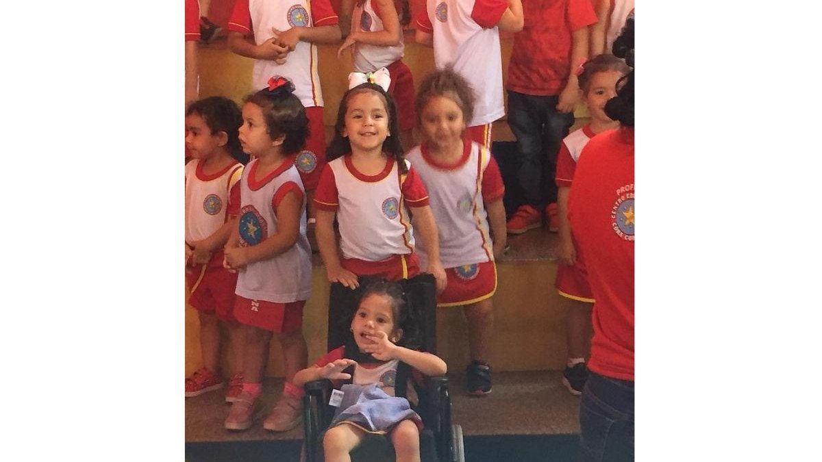 Amiga ajuda menina cadeirante durante festinha da escola (foto: reprodução/Video)