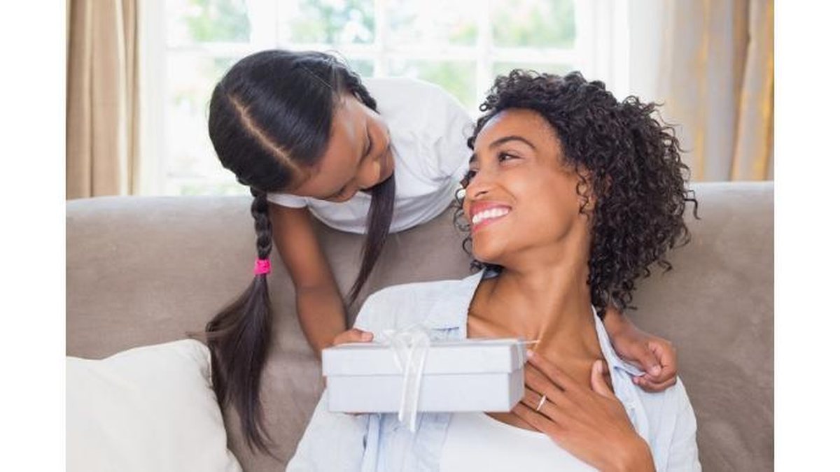 pretty-mother-sitting-on-couch-with-daughter-offering-a-gift-picture-id817290382 - Foto: Istock