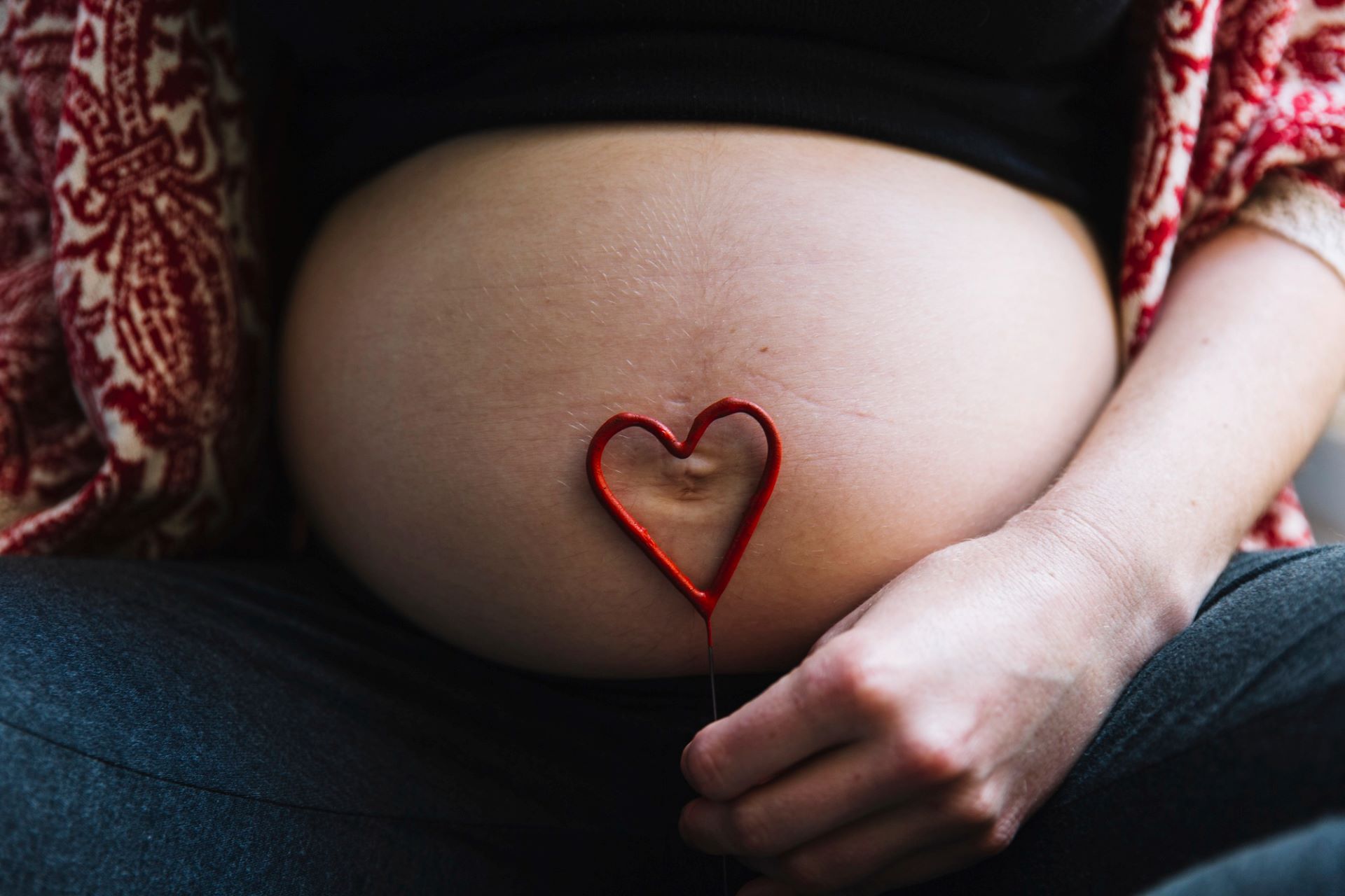 mulher com barriga de grávida e um coração
