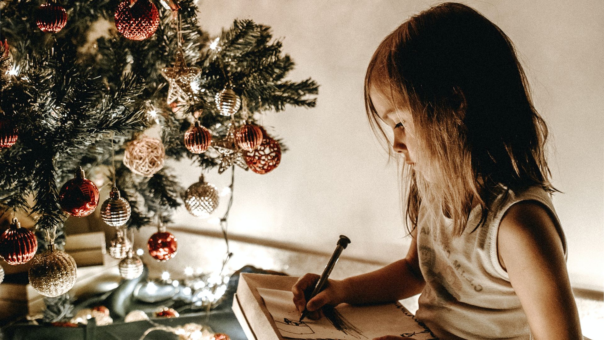 Menina escrevendo carta para o Papai Noel em cenário natalino
