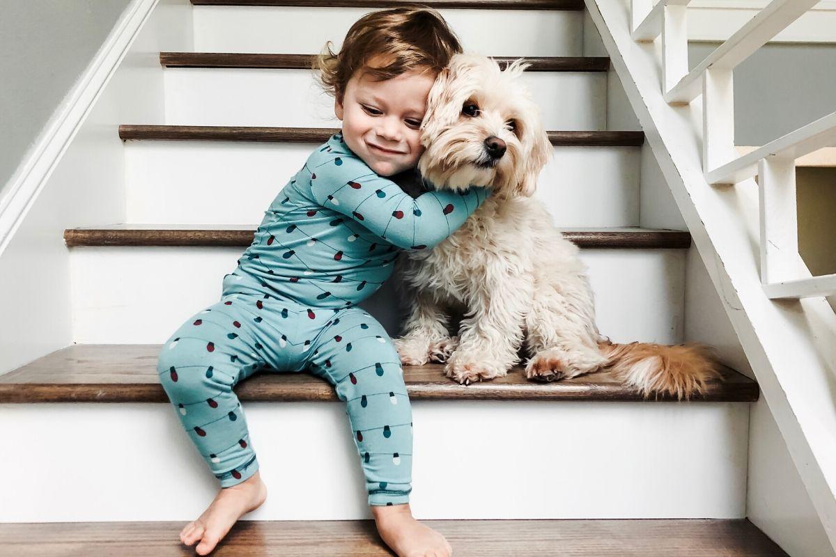 Criança abraçando cachorro