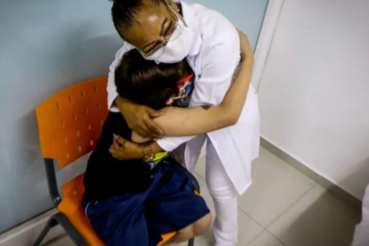 Criança abraça enfermeira após se vacinar