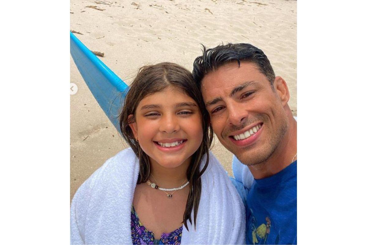 Cauã Reymond e Sofia, também na praia, compartilhando sorrisos de pai e filha.