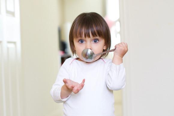 little-girl-with-spoon-in-mouth-picture-id516423951