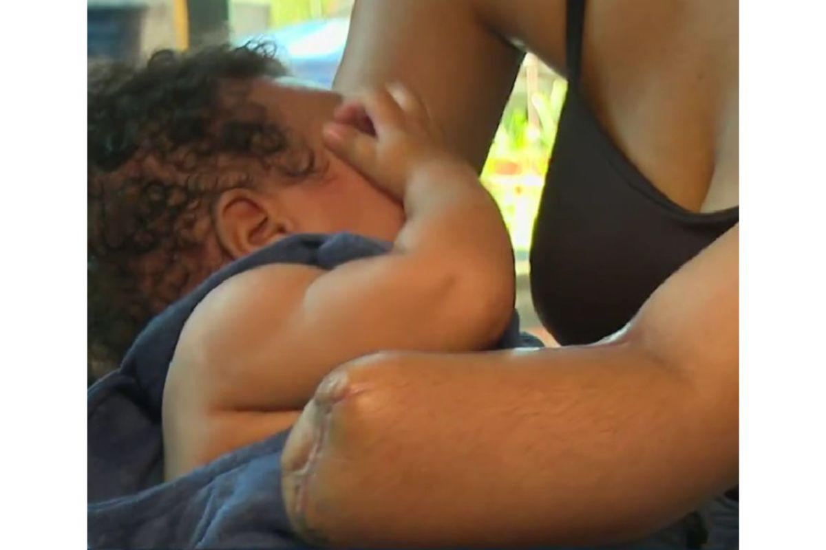 Mulher com mão amputada segurando bebê no colo