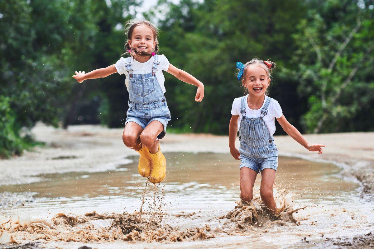 Crianças sorrindo pulando na lama 