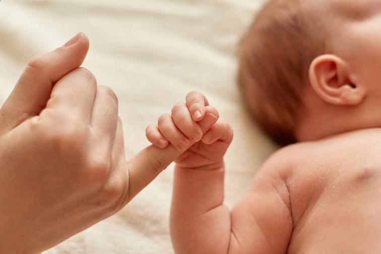 Bebê segurando dedo de mulher