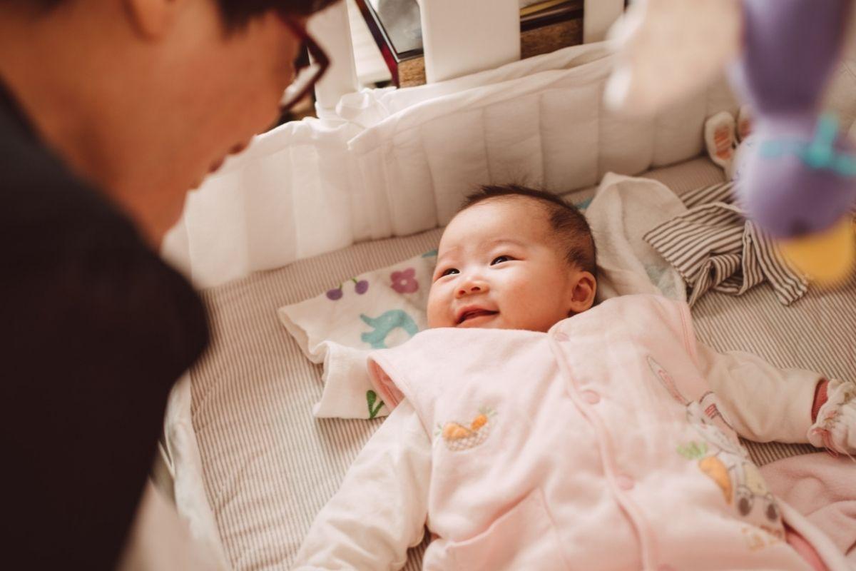 bebê japonesa sorrindo em berço olhando para o pai