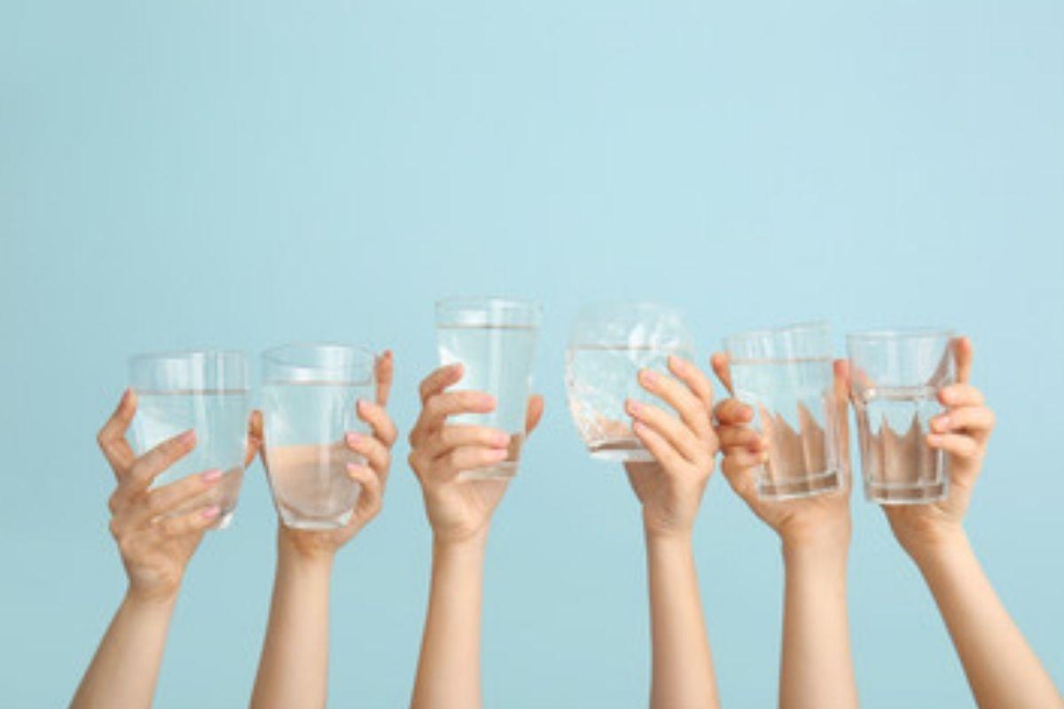 Mãos segurando copos de água