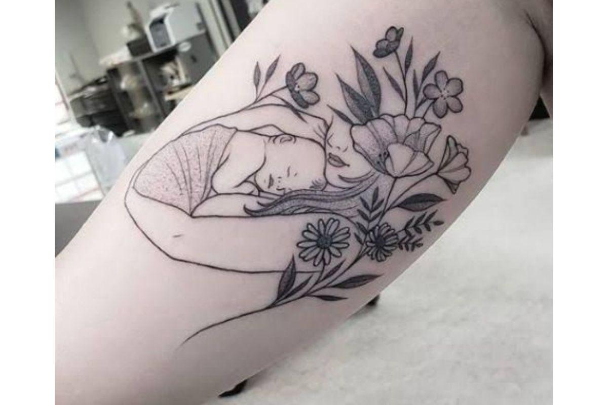 Tatuagem de mãe abraçando filho com flores 