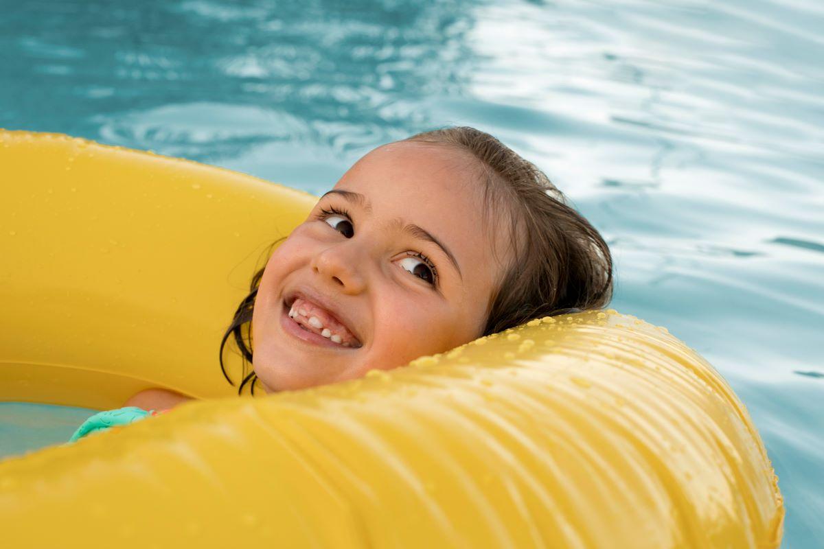 menina em boia amarela em piscina