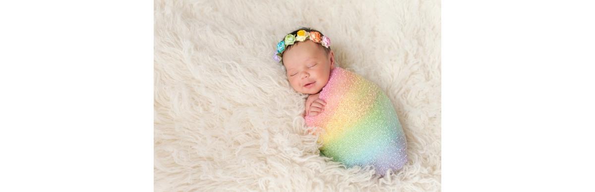 smiling-newborn-baby-girl-wearing-a-rainbow-colored-swaddle-picture-id485885456